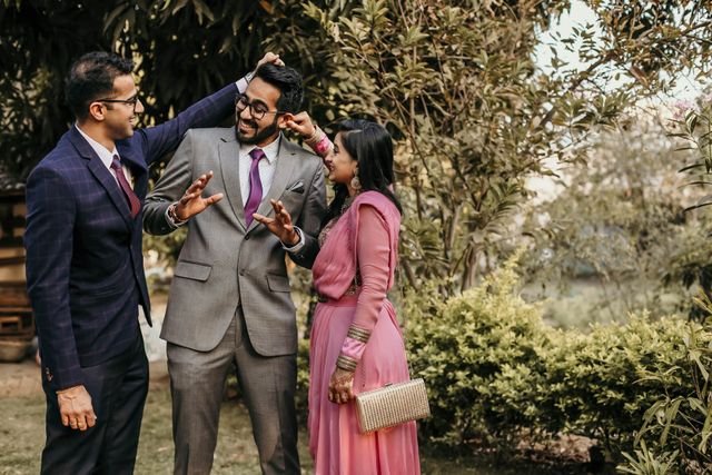 A joyous outdoor wedding celebration with friends in traditional Indian attire, sharing laughter and happiness.